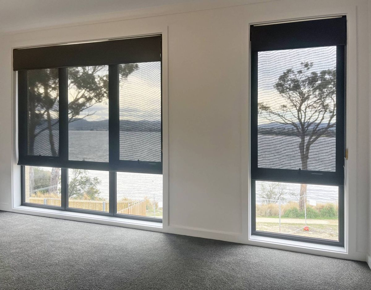 Dual roller blinds in a living room looking out over the water